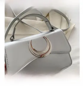 Détail du sac à main en cuir grainé avec boucle en croissant argenté et surpiqûres fines