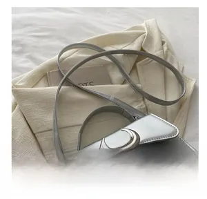 Détail de la boucle lune argentée et du cuir texturé sur un sac carré chic et moderne