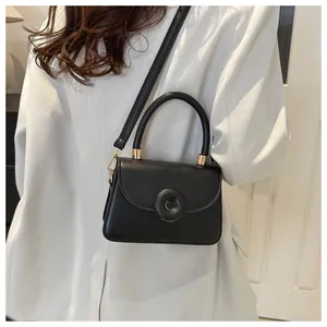 Detail of black vintage leather handbag with oversized buckle and gold-tone metal hardware