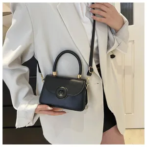 Detail of minimalist black crossbody bag with round buckle and adjustable strap