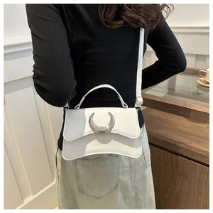 Détails d'un sac bandoulière en cuir blanc avec une boucle en croissant argenté