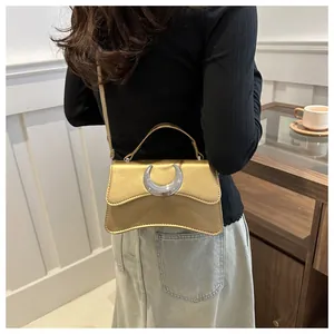 Détail du sac à bandoulière doré champagne avec boucle en croissant sur un modèle élégant