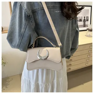 Détail du sac à bandoulière beige avec boucle lune argentée et texture en cuir grainé