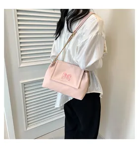 Gros plan du sac à bandoulière rose avec broderie papillon et bandoulière en chaîne métal