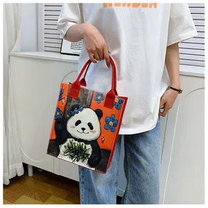 Close-up of bright orange felt tote bag featuring a cute cartoon panda and red handles
