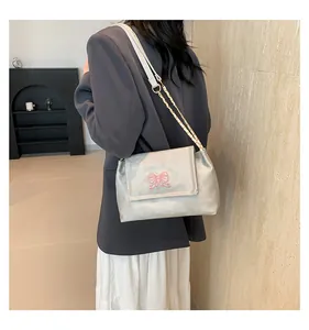 Sac bandoulière argenté avec broderie papillon rose et chaîne dorée sur mannequin