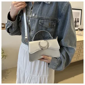 Détail de la boucle lune argentée sur un sac bandoulière en cuir texturé élégant