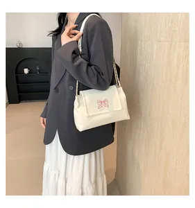 Détail du sac à bandoulière blanc cassé avec broderie papillon et chaîne dorée