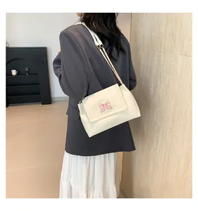 Vue latérale détaillée du sac à bandoulière blanc cassé avec broderie papillon et chaîne