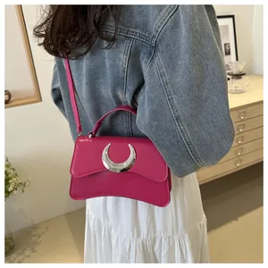 Détail d'un sac bandoulière rose fuchsia avec boucle métallique argentée en forme de lune