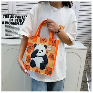 Detail of orange felt tote bag featuring panda illustrations and thick carry handles