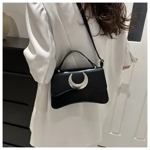 Détail du sac à bandoulière noir avec boucle en lune et texture en cuir grainé
