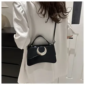 Détail du sac à bandoulière en cuir noir avec boucle lune argentée porté par un mannequin