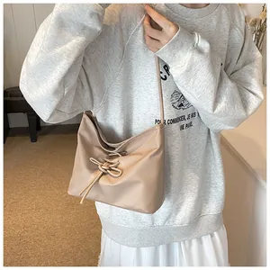 Detail of beige ballet style bucket bag with drawstring bow and soft pleated texture