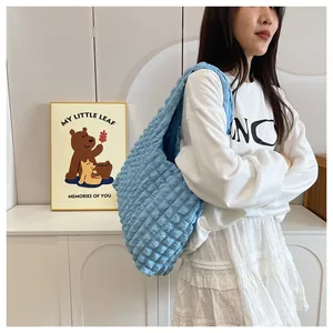Close-up of light blue popcorn texture tote bag worn by a model in a minimalist setting