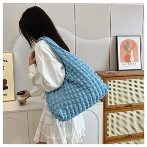Detail view of light blue popcorn textured tote bag worn by a model in a cozy room