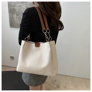 Detail view of large cream leather tote bag with dark brown straps and chain links
