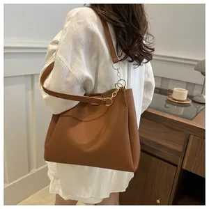 Detail of brown litchi grain leather tote bag featuring elegant gold chain strap accents