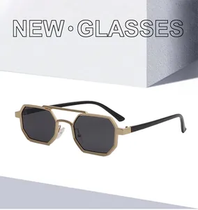 Detail of polygonal gold metal sunglasses with double bridge and dark lenses on white block