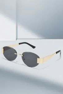 Detail view of rimless oval sunglasses with gold metal temples and smoke grey lenses