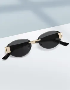 Detailed view of rimless oval sunglasses featuring gold metal bridge and black lenses