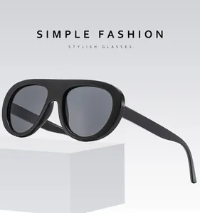 Detail view of retro aviator sunglasses with thick black frames on a white platform