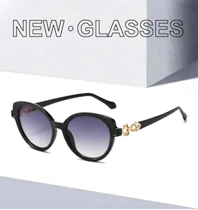 Detail of black cat-eye sunglasses with purple gradient lenses and gold hinge accent
