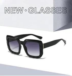 Detail of square black oversized sunglasses with gradient purple lenses on stone display