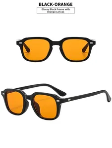 Detail of square black sunglasses with orange lenses and silver rivets on the frame