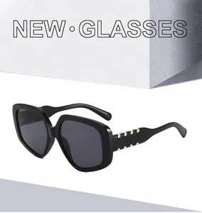 Détail de lunettes de soleil carrées avec accents métalliques dorés sur les branches noires