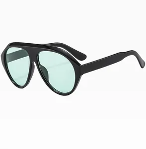 Detail of oversized aviator sunglasses featuring black frames and mint green lenses