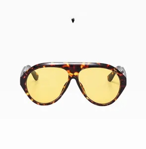 Detail of oversized demi-shell sunglasses with vibrant yellow lenses and sleek frames