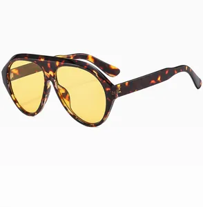 Detail view of oversized aviator sunglasses with yellow lenses and tortoise shell frames