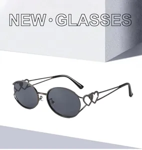 Detailansicht einer schwarzen ovalen Sonnenbrille mit doppelten Herz-Metall-Akzenten am Bügel