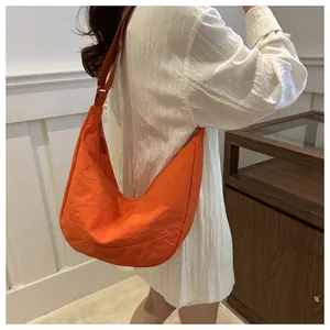 Detail van de levendige oranje halve maan crossbodytas van nylon met een brede riem
