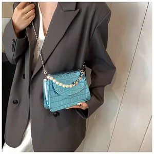 Dettaglio borsa quadrata azzurra con stampa cocco ed elegante catena di perle