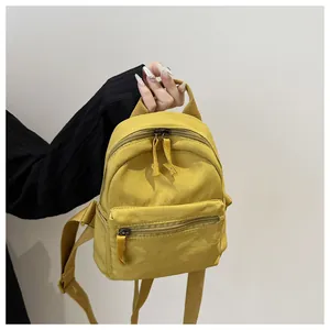 Detail of yellow canvas mini backpack with a zippered front pocket and adjustable straps