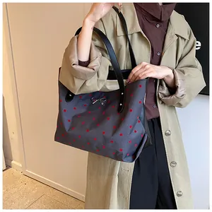 Close-up of gray polka dot tote bag with a silver metal bow and black leather handles