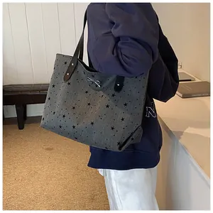 Detail of grey tote bag with black star patterns and elegant metal bow accent