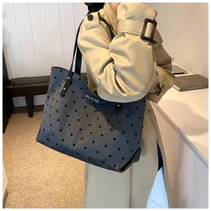 Deep grey polka dot tote bag with black bow patterns shown on a model in a beige coat