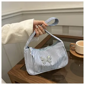Close-up of light blue shoulder bag with pleated texture and silver butterfly buckle