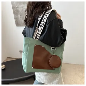 Detailed view of green canvas tote bag with brown leather pocket and coin purse.