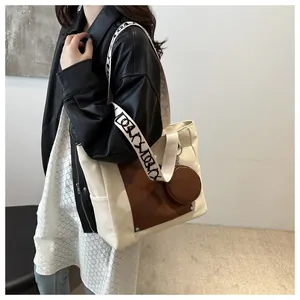 Close-up view of a large canvas tote bag featuring contrast leather pocket detail