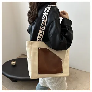 Detailed view of a large canvas tote bag with a brown pocket worn by a model