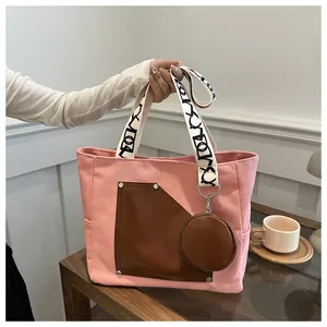 Detail view of pink canvas tote bag with brown faux-leather pocket and round pouch