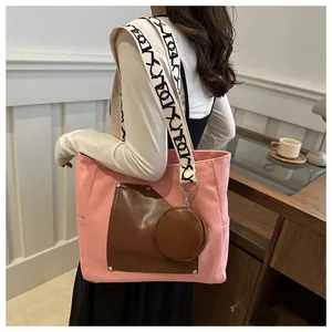 Close-up of a pink canvas tote bag with brown patchwork pocket and a wide patterned strap.
