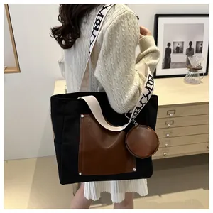 Detailed view of black canvas tote bag with brown leather pocket and patterned strap