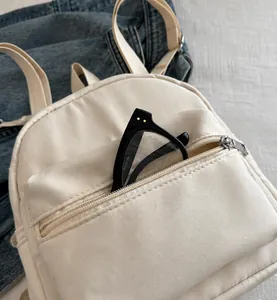 Detalle del bolsillo delantero de la mini mochila beige con gafas para uso diario