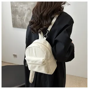 Vista trasera de una mini mochila beige de nailon en modelo con herrajes plateados