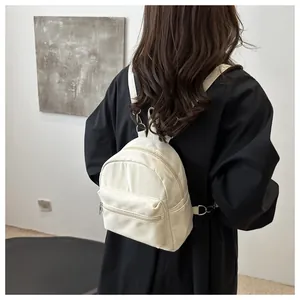 Vista de detalle de mini mochila de nailon blanco crema con correas en modelo real